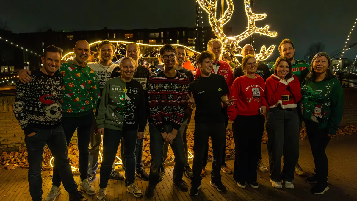 Het team in kersttruien buiten bij de kerstverlichting