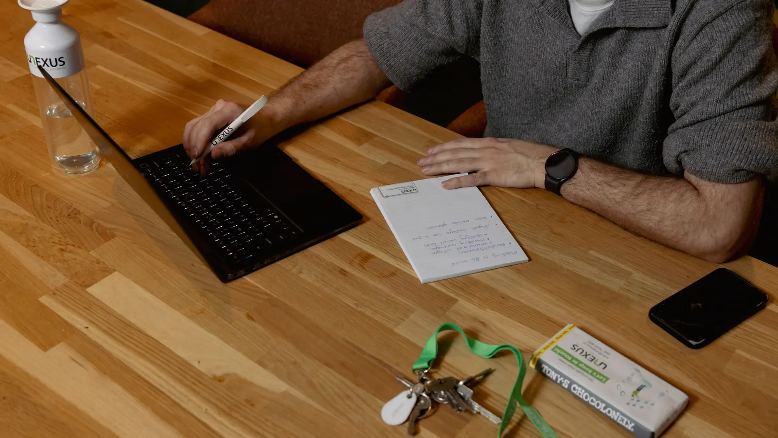 Een blocnote met handgeschreven aantekeningen naast een laptop op een bureau